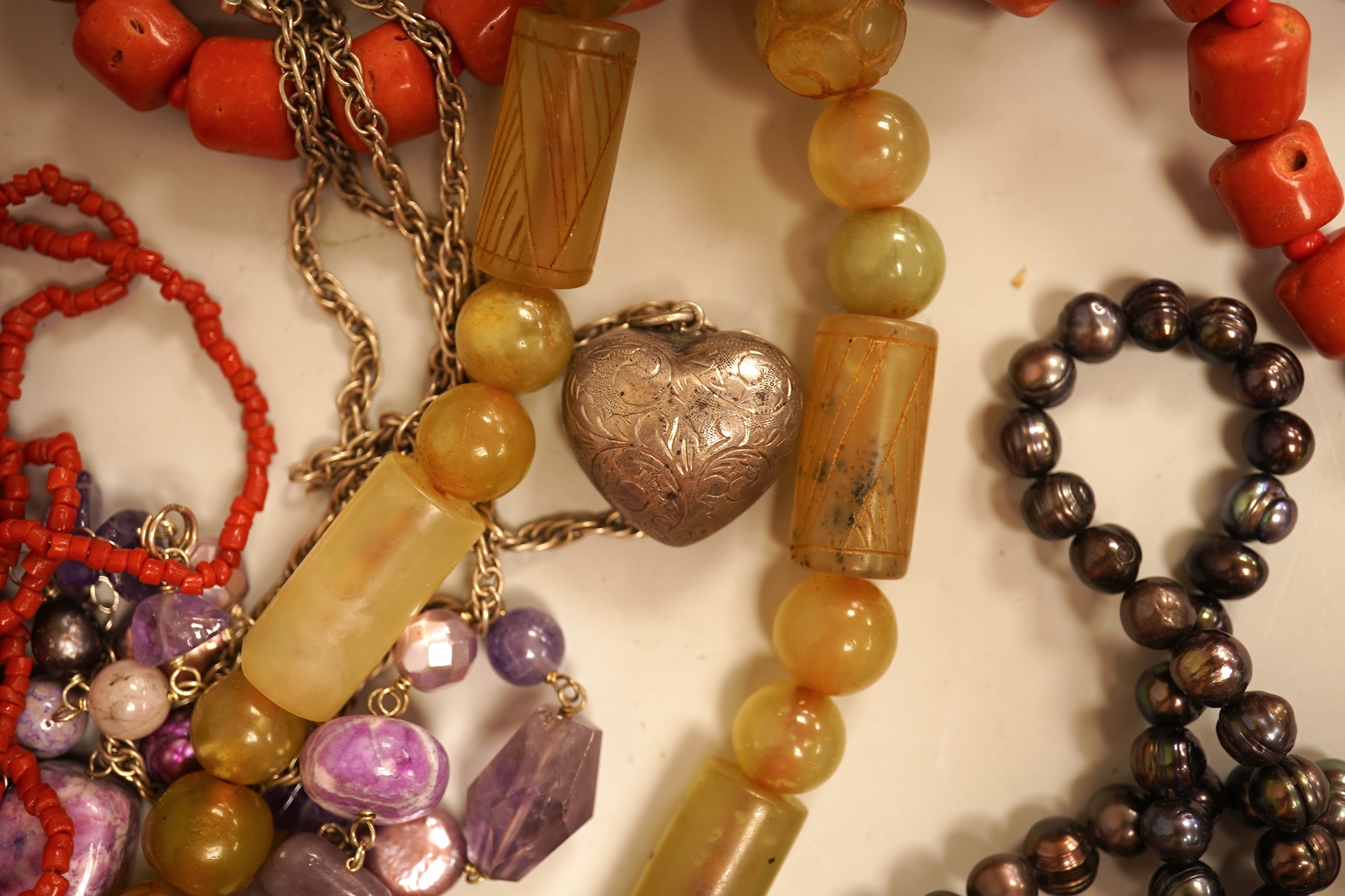 A small group of sundry jewellery including a simulated amber necklace and a multi strand coral bead necklace, etc.